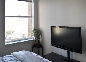 a flat screen tv in a bedroom with a window at Downtown Aurora River Facing Gem in Aurora