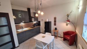 a kitchen with a white table and a red chair at Appart Hôtel Le Ptit Bec in Bègles