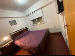 ein Schlafzimmer mit einem Bett mit einer lila Bettdecke und einem Fenster in der Unterkunft EL AMANECER - APART HUASI III in San Fernando del Valle de Catamarca