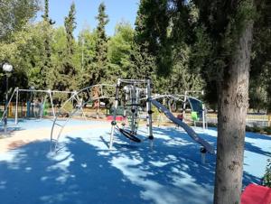 a park with an empty playground with a tree at Hermes Riviera view in Athens