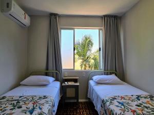 a room with two beds and a window with a palm tree at Casa das Palmeiras in Piratuba