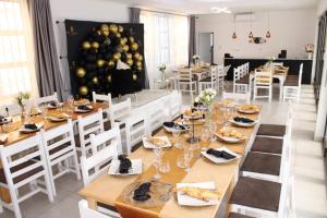 a dining room with a long table and white chairs at The Space Guesthouse Mondlo in Mondlo