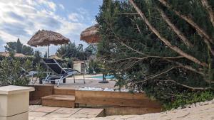 a patio with two chairs and an umbrella at Studio cosy neuf calme -Parking Terrasse privée Piscine 5mn Gare TGV Aix et ZA Aix la Duranne 15 mn Aéroport Marseille in Cabriès