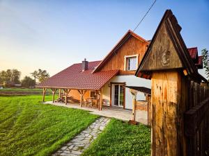a house with a wooden roof on a green field at Zakątek - Żabi Kraj in Mnich