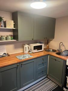 a kitchen with green cabinets and a microwave on a counter at Turning Tides Holiday Cottage in Great Yarmouth