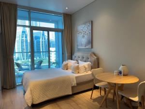 迪拜Studio One Dubai Marina - TIE Vacation Homes的一间卧室，里面有一张床、一张桌子和一扇窗户