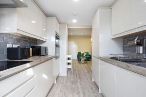 a kitchen with white cabinets and black appliances at OnSiteStays - Stylish 5 bedroom house with 3 bathrooms in Dartford +15 photos