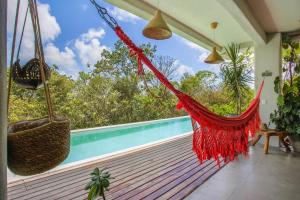a hammock on the porch of a house with a pool at Casa Dahomey in Pipa