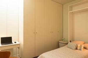 a bedroom with a bed and a desk with a laptop at Bisas Villa in Caminha
