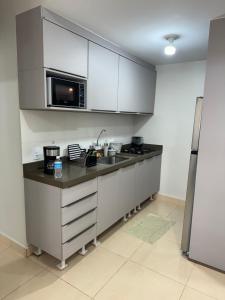 a kitchen with white cabinets and a microwave at Apto 202, Torre 1 in Lucas do Rio Verde