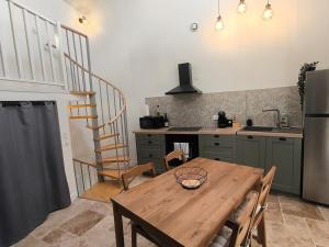 a kitchen with a wooden table and a staircase at Gîte de la Cheminée in Saint-Privat