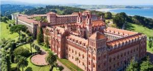 an aerial view of a large brick building with trees at La Aldea 3 , CENTRO de Comillas, Parking Público y vistas Universidad Pontificia in Comillas