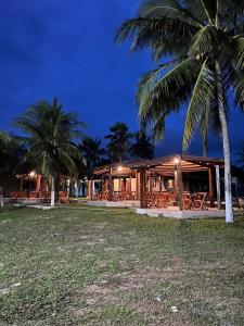 a building with tables and palm trees at night at Pousada Brisa do Lago Camocim in Camocim +7 photos