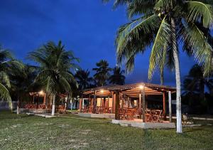 a restaurant with tables and palm trees at night at Pousada Brisa do Lago Camocim in Camocim