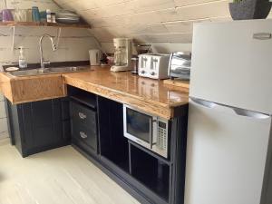 a kitchen with a white refrigerator and a microwave at Le vieux poulailler édifice patrimonial New-Richmond Gaspesie in New Richmond