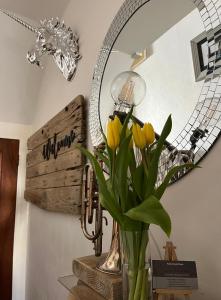 a vase with yellow flowers in front of a mirror at Kelston Guest House in Weymouth