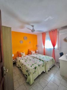 a bedroom with a bed with orange walls and a window at Bèl Péyi - Bas de Villa T4 Proche de la Plage in Bouillante