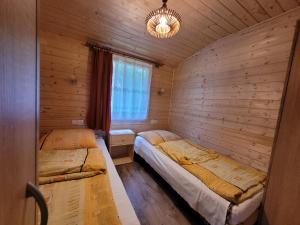 a bedroom with two beds in a wooden cabin at Kwatery U Marka in Gowidlino