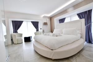 a white bedroom with a large white bed and a couch at Domus De Cinti in Tivoli
