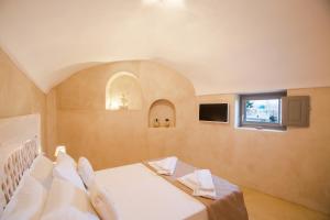 a bedroom with a bed with white sheets and a window at LoveNest in Akrotiri