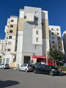 twee auto's geparkeerd voor een gebouw bij Darkoum Apartment Anza in Agadir
