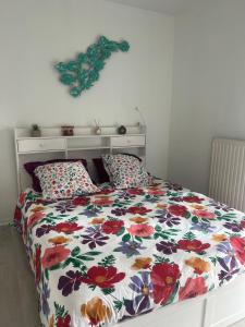 a bed with a floral comforter and two pillows at Whoua Charmant appart Mérignac in Mérignac