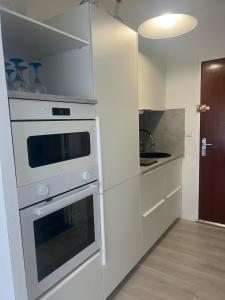 a white kitchen with a stove and a sink at Whoua Charmant appart Mérignac in Mérignac