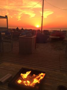 een vuurplaats op het strand met een zonsondergang op de achtergrond bij Beach Hotel Katwijk in Katwijk