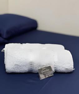 ein weißes Handtuch auf einem Bett mit einem Buch darauf in der Unterkunft Conforto e Praticidade em Araxá in Araxá