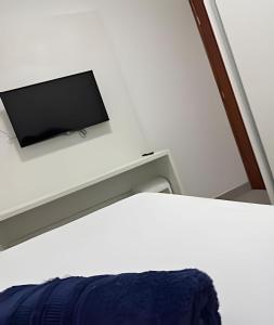 Zimmer mit einem Bett und einem TV an der Wand in der Unterkunft Conforto e Praticidade em Araxá in Araxá
