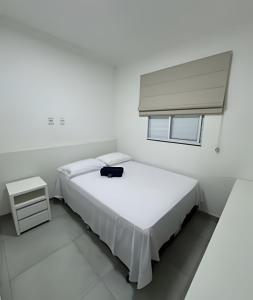 ein weißes Schlafzimmer mit einem Bett und einem Fenster in der Unterkunft Conforto e Praticidade em Araxá in Araxá