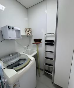 eine Waschküche mit einer Waschmaschine und einem Regal in der Unterkunft Conforto e Praticidade em Araxá in Araxá + 28 Fotos