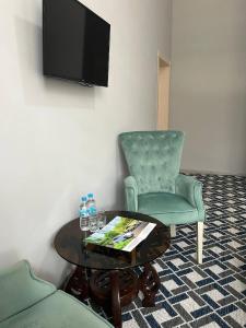sala de estar con mesa, silla y TV en Grand Mountains Hotel, en Baysun