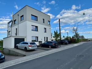 a white building with cars parked in a parking lot at Penthouse mit Ausblick in Bad Schwalbach