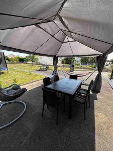 a table and chairs under a large umbrella at Les mésanges, 10m Zoo de Beauval, climatisation in Noyers-sur-Cher