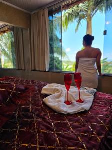 Eine Frau steht vor einem Bett mit zwei Weingläsern. in der Unterkunft Refúgio Romântico com Pet Friendly 38min de ÁGUAS CLARAS BRASÍLIA in Brasilia