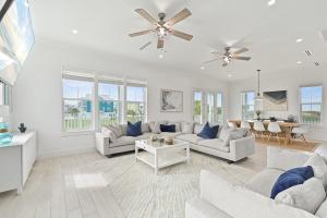 a living room with white furniture and a ceiling fan at Cueva de Piratas is Luxury with Beach and Pools in Galveston