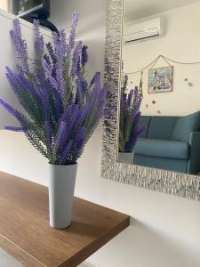 a white vase with purple flowers on a table next to a mirror at Francy s Marzamemi Home in Marzamemi +22 photos