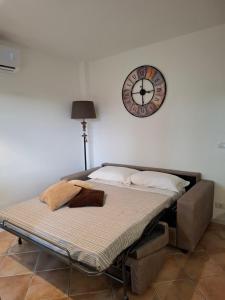 a bed in a room with a clock on the wall at Le Mimose Garden in Bordighera
