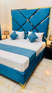 a bed with blue and white pillows on it at Holiday Guest House Lahore in Lahore