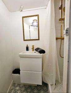 a white bathroom with a sink and a mirror at Studio Cœur de Deauville à 10 minutes à pied de la plage in Deauville