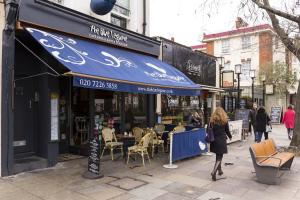 un restaurante con toldo azul en una calle de la ciudad en Trendy Spacious 1 Bedroom Flat, en Londres