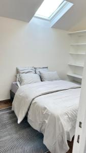 a white bedroom with a bed with a window at MEZZANINE 17 Rue de la Fraternité DEUX CHAMBRES AVEC PARKING in Drancy