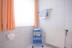 een wit betegelde badkamer met een radiator en handdoeken bij Haus-Karin-Ferienwohnung-1 in Büsum +20 foto's
