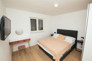 a small bedroom with a bed and a tv at DiDixi Apartments in Pakoštane +21 photos