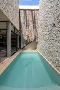 an empty swimming pool in a building with a stone wall at 2 Tropical Bohemian Villas-2 Priv Pool-BBQ 3A-3B in Tulum