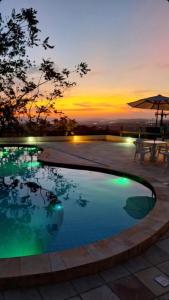 ein Swimmingpool mit einem Sonnenuntergang im Hintergrund in der Unterkunft Topo da Montanha 205 in Chã Grande