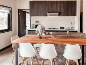 a kitchen with a wooden table and white chairs at apartamento campestre con terraza in Puerto Varas