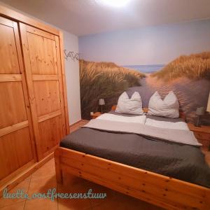 a bedroom with a bed with a painting of a beach at luette oostfreesenstuuv in Holtgast