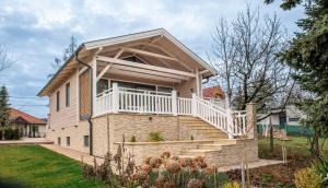 a house with a balcony and stairs in a yard at Panoráma Cottage in Nyúl